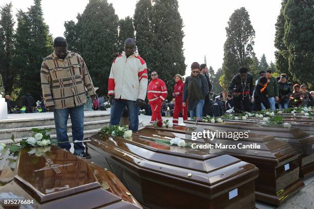 Two men stand in front of the coffins, during the funeral of the 28 migrant women who died in a shipwreck as they sought to reach Italy.