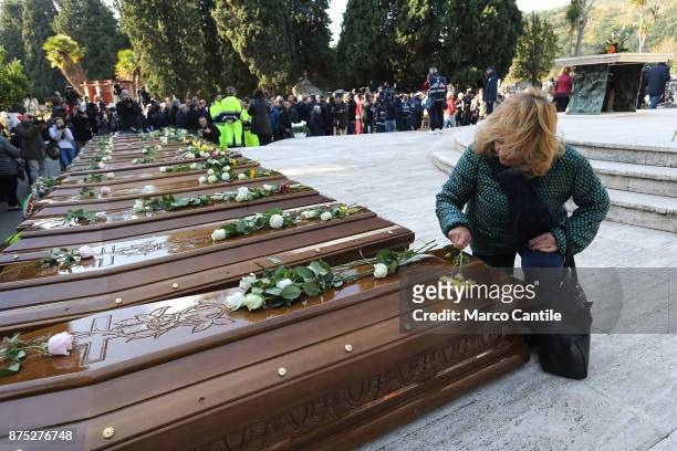 Woman kneeling in front of the coffins leaves a flower, during the funeral of the 28 migrant women who died in a shipwreck as they sought to reach...