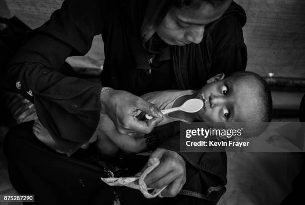 Rohingya Muslim refugee Hamida Khatun feeds her malnourished one- year-old son Ibrahim high calorie peanut paste at a field clinic by the NGO Action...