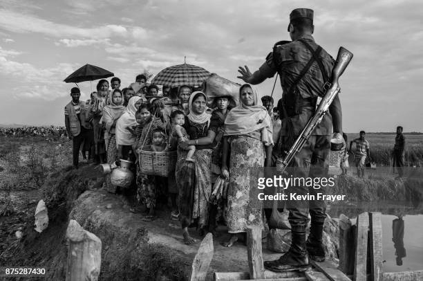 Bangladeshi border guard from the BGB gestures as he controls a crowd of Rohingya Muslim refugees waiting to proceed to camps after crossing the...