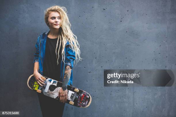 jeune femme tenant la planche à roulettes à l’extérieur, contre le mur gris - figure skating photos photos et images de collection