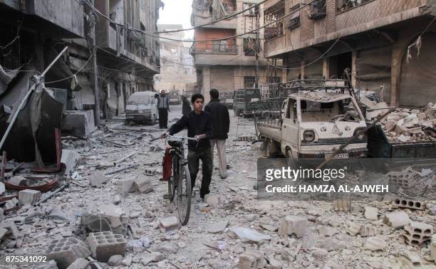 Syrian boy pushes a bicycle down a street amidst the destruction following reported shelling by Syrian government forces, in the rebel-held town of...
