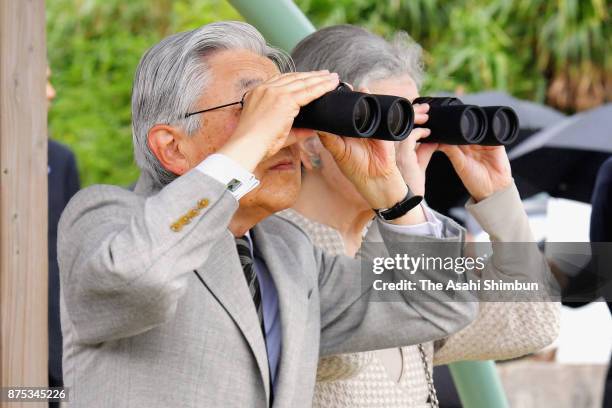 Emperor Akihito and Empress Michiko watch through binoculars during their visit to Yurigahama Beach at Yoronjima Island on November 17, 2017 in...