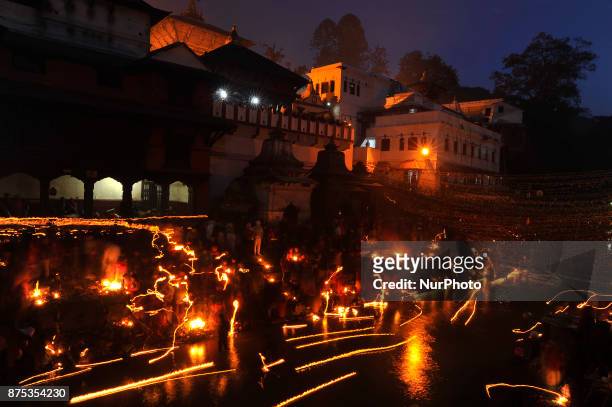 Oil lamps offered by devotees illuminate the Bagmati River flowing through the premises of the Pashupatinath Temple during the Bala Chaturdashi...