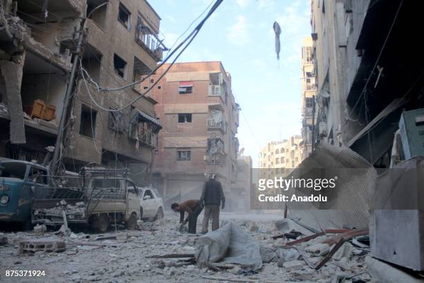 Two man are seen among collapsed buildings after Assad regime's warcrafts carry out intensifying airstrikes over residential areas of Arbin town of...