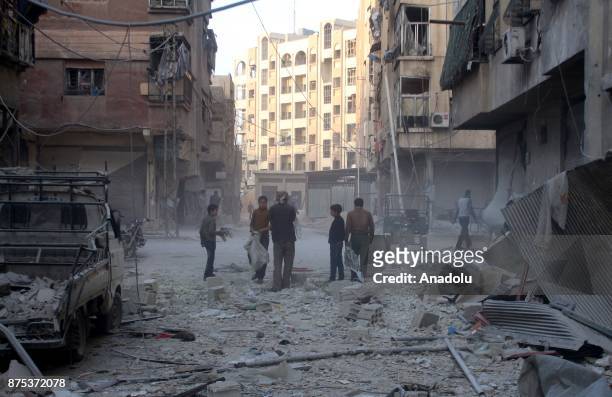 Men are seen among collapsed buildings after Assad regime's warcrafts carry out intensifying airstrikes over residential areas of Arbin town of the...