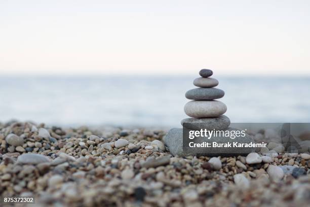 balanced stones on a pebble beach - balance stones stock pictures, royalty-free photos & images