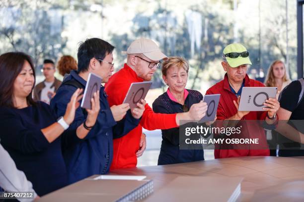 People try out the augmented reality system that shows what the finished Apple Park will look like at the opening of the Apple Park Visitor Center on...