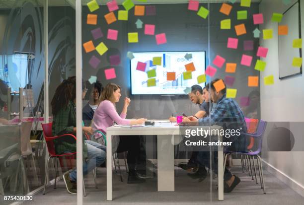 gruppo multietnico in una riunione del consiglio di amministrazione idee di brainstorming con note consiglianti sul vetro della finestra - ricerca di mercato foto e immagini stock
