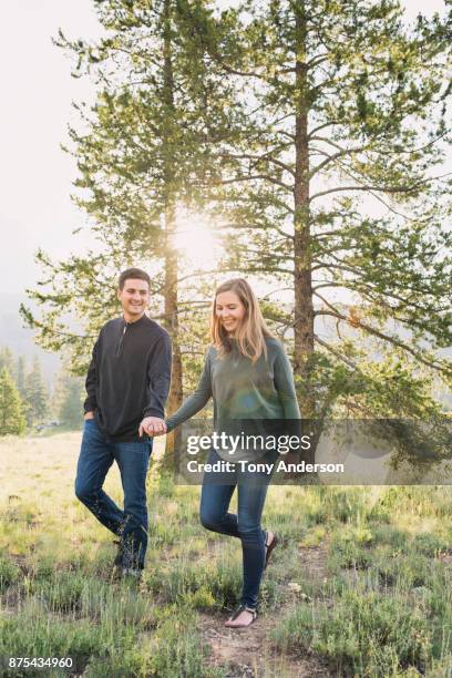 young hetrosexual couple walking in forest in summer - couple jeans shirt stock-fotos und bilder