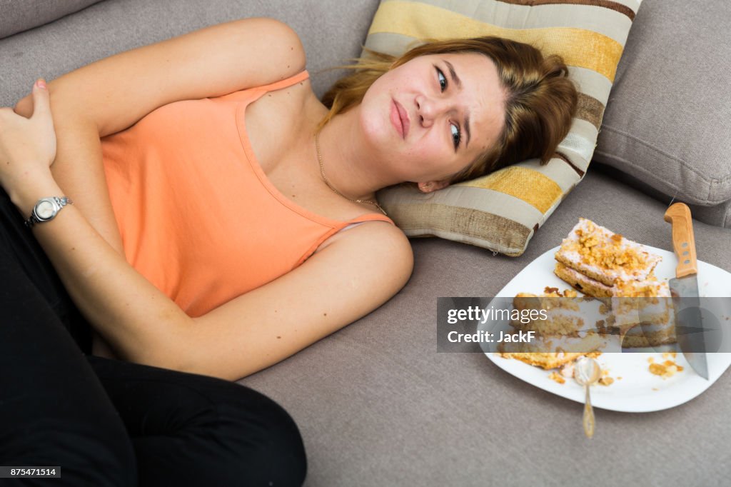 Meisje heeft een maagpijn na het eten veel taart