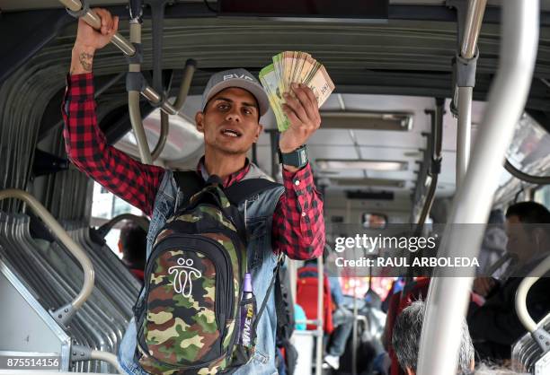 Venezuelan national Jhonger Pina sells candies and shows Bolivar bills as a curiosity to passengers, in exchange for local coins on a bus in Bogota,...