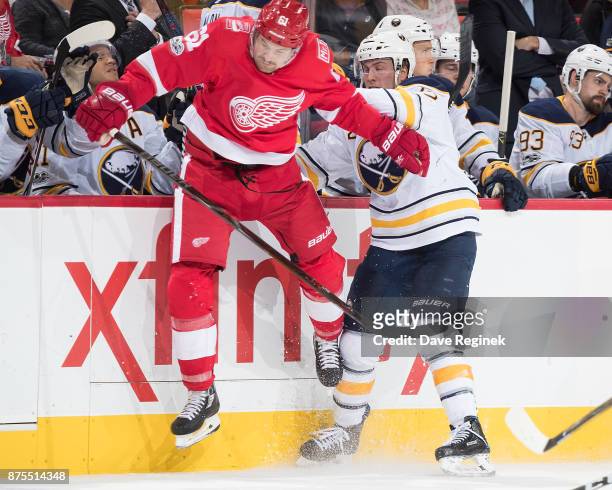 Johan Larsson of the Buffalo Sabres battles along the boards with Xavier Ouellet of the Detroit Red Wings during an NHL game at Little Caesars Arena...