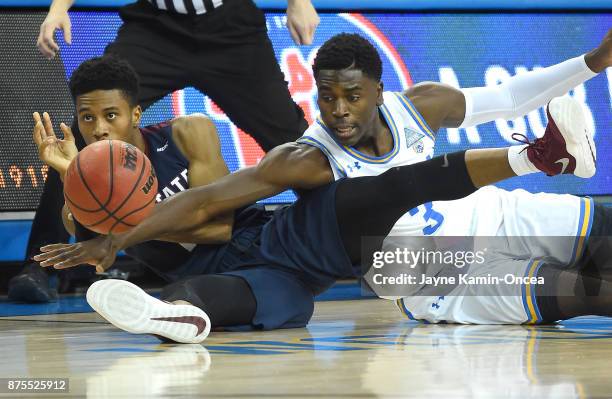 Aaron Holiday of the UCLA Bruins and Janai Raynor Powell of the South Carolina State Bulldogs reach for a loose ball in the first half of the game at...