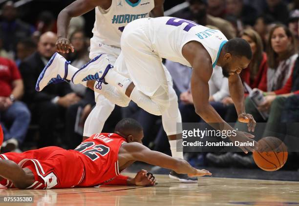 Kemba Walker of the Charlotte Hornets leaps over Kris Dunn of the Chicago Bulls trying to chase a loose ball at the United Center on November 17,...