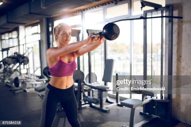 mujer joven haciendo ejercicios de kettlebells en el gimnasio - columpiarse fotografías e imágenes de stock