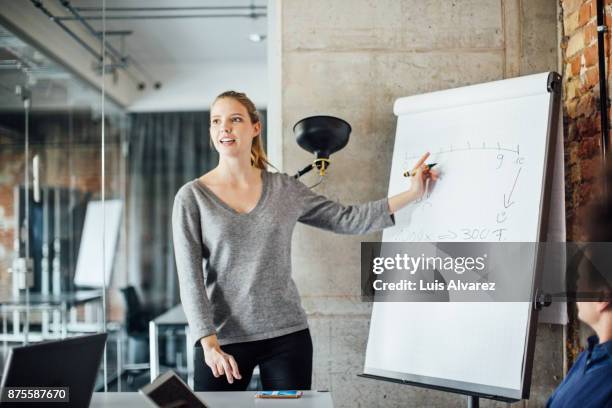 confident businesswoman writing on flip chart - rotafolio fotografías e imágenes de stock