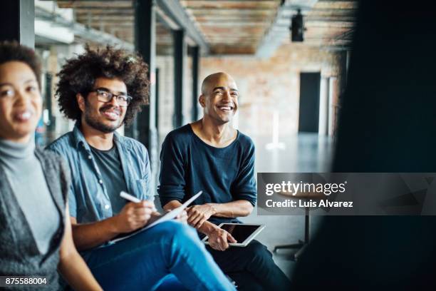 smiling colleagues listening in meeting - briefing stock-fotos und bilder