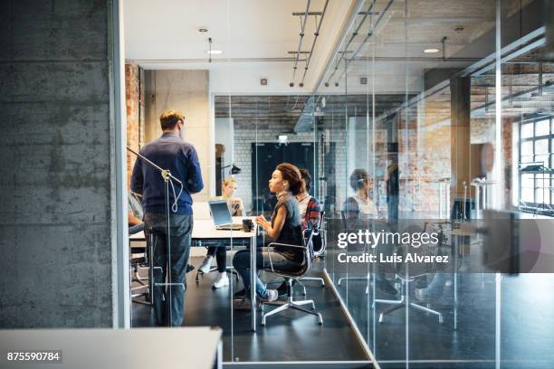 businessman giving presentation to colleagues seen through glass - fotografato da una finestra foto e immagini stock