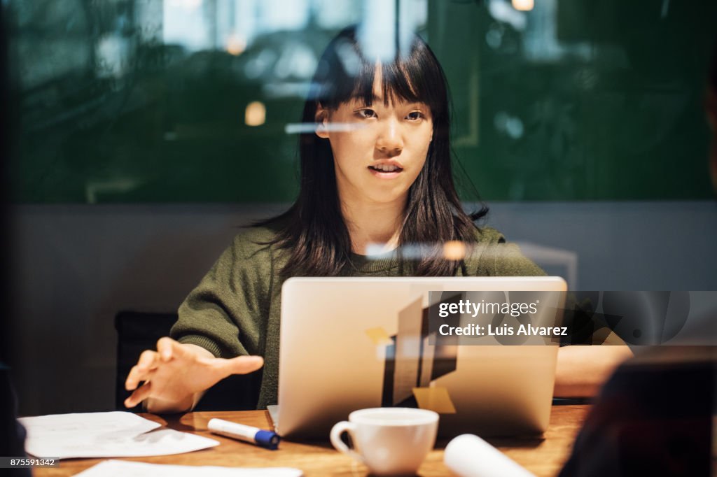 Businesswoman discussing while working late on laptop