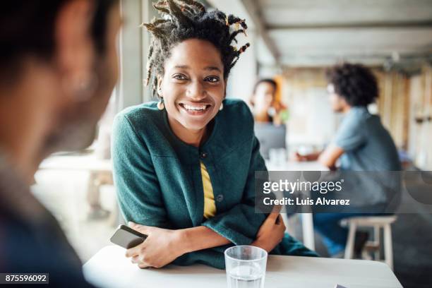 smiling businesswoman sitting with colleague in cafeteria - messa a fuoco differenziale foto e immagini stock