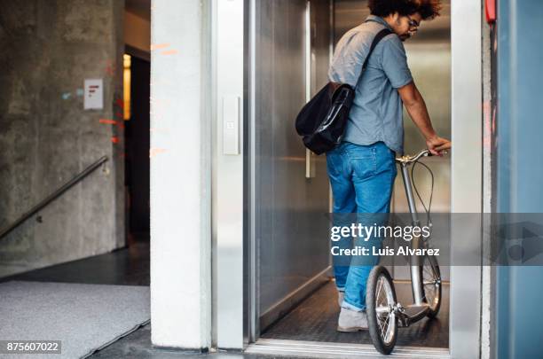 businessman walking with push scooter - elevator doors stock-fotos und bilder