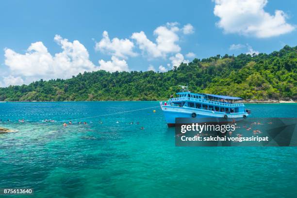 idyllic view of people snorkelling around island and their tour boat, koh chang island, trat, thailand. - koh chang stock pictures, royalty-free photos & images