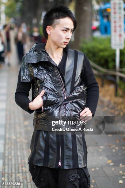 Anri, , wearing a Sexprime black jacket, Julius cargo black pants, leather black shoes, and a zipped tunic leather and black shirt, stops for a...