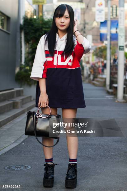 Mizuki Aihara , wearing an oversized Fila red, white and blue top, platform black shoes with wide ribbon black laces, and a leather black bag with...