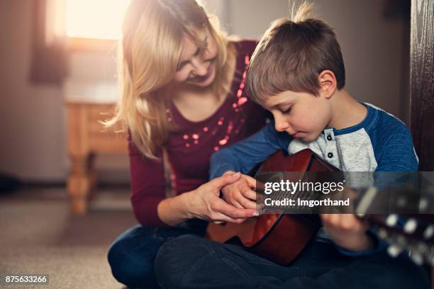 mother teching son to play guitar - teching imagens e fotografias de stock