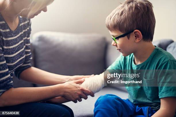 mother tending to her son's wounded arm - hand bandages stock pictures, royalty-free photos & images