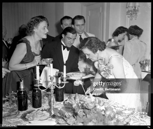 In a charming hostess gown of white lace, Mrs. Perle Mesta serves her guests at the first big party in the little house in Luxembourg where she...