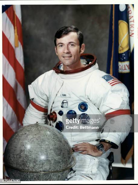 Portrait of astronaut John W. Young, Apollo 16 Mission Commander, posing with a globe of the moon at the Madded Spacecraft Center in Houston.