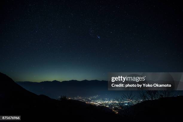 constellation orion and city light seen from senjojiki karl - japan skyline stock-fotos und bilder