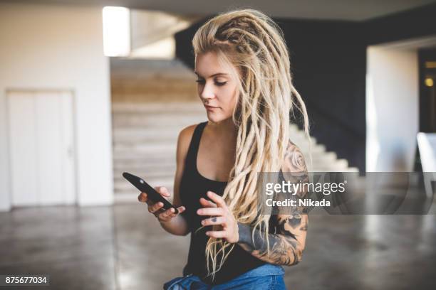 jovem mulher com mensagem de dreadlocks sms no telemóvel - rasta - fotografias e filmes do acervo