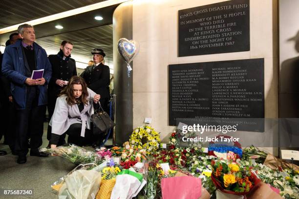 Woman lays flowers by a memorial plaque during a service to mark the 30th anniversary of the King's Cross fire at King's Cross Station on November...