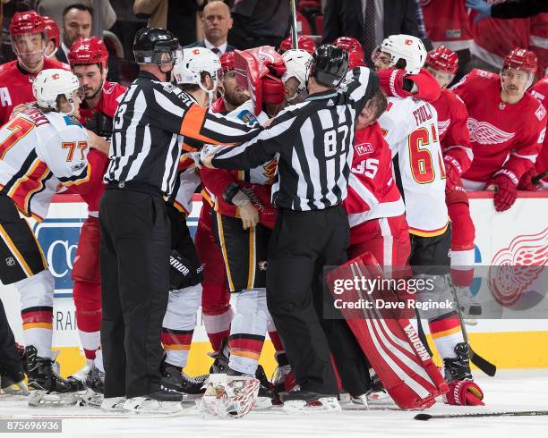 Referee Kevin Pollock and linesman Devin Berg try to break up a multi player fight in front of the benches during an NHL game at Little Caesars Arena...