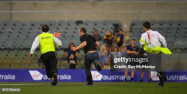 Perth , Australia - 18 November 2017; A man who ran on to the pitch after the game is pursued by security personnel after the Virgin Australia...