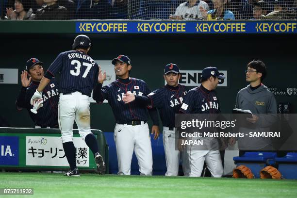 Pinch runner Outfielder Masayuki Kuwahara of Japan high fives with team mates after scoring a run by the RBI single of Infielder Yota Kyoda in the...