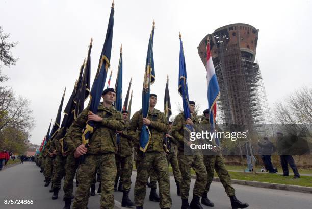 Croatian soldiers carry flags as they lead a procession titled a "Memory Column" as part of a march in Vukovar on November 18 during a ceremony to...