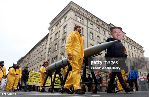 An activist with a mask of Kim Jong-un, chairman of the Workers' Party of Korea and supreme leader of North Korea, marches with a model of a nuclear...