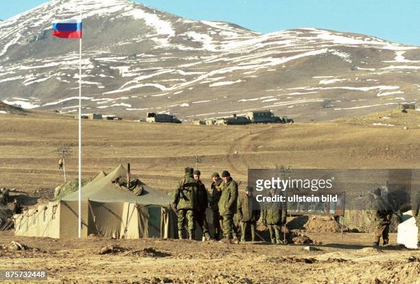 Krieg im Kaukasus, Tschetschenienkonflikt: ein russisches Militärlager am Fuße des Kaukasus. Soldaten stehen neben ihrem Mannschaftszelt auf der...