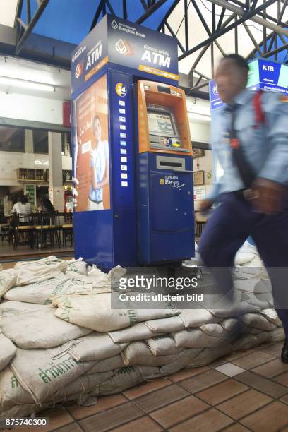 Ein Mann in Uniform geht an einem Geldautomaten vorbei, der mit gefuellten Sandsaecken gegen die Fluten des Chao Praya geschuetzt worden ist. Der...