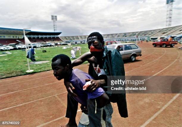 Fussballstadion Kigali: verletzter Tutsi wird von einem anderen getragen - Mai 1994