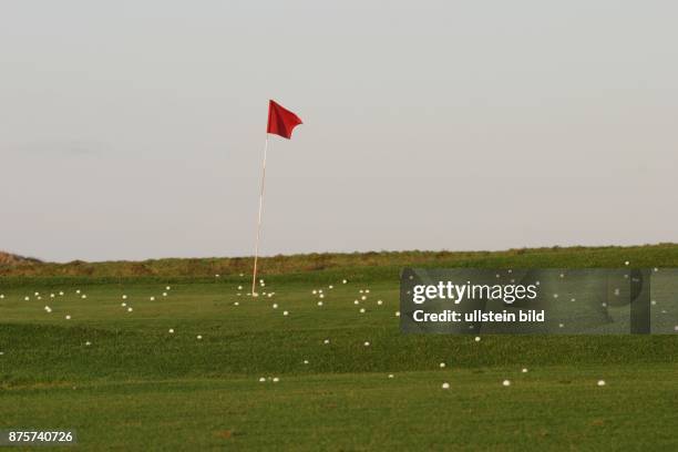 Golfplatz: Rote Fahne und Golfbälle auf dem Green