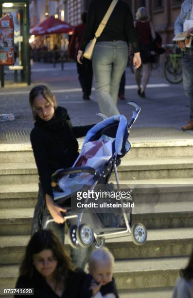 Frauen tragen einen Kinderwagen und ein Kleinkind eine Treppe zum S-Bahnhof hinunter