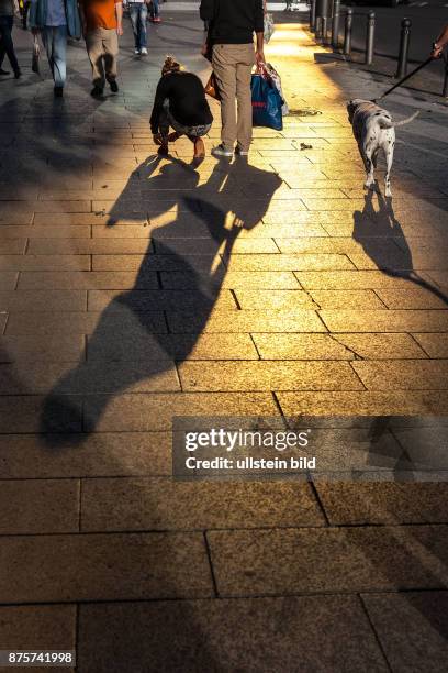 Deutschland Germany Berlin Passanten werfen ihre Schatten auf Berlin populäre Einkaufsstrasse, den Tauentzien. Das Gold einer Glasfassade spiegelt...