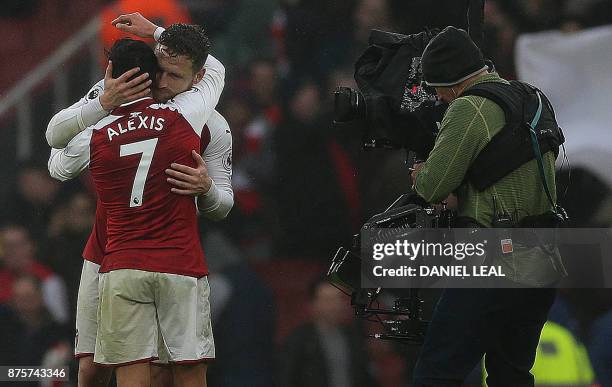 Televsion camnera operator film as Arsenal's German defender Shkodran Mustafi embraces Arsenal's Chilean striker Alexis Sanchez following the English...