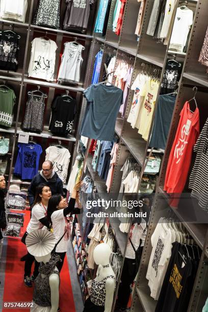 Deutschland Germany Berlin Eröffnung der japanischen Modekette Uniqlo am Tauentzien. Verkäuferin hängt ein T-Shirt mit einer Teleskopstange zurück in...