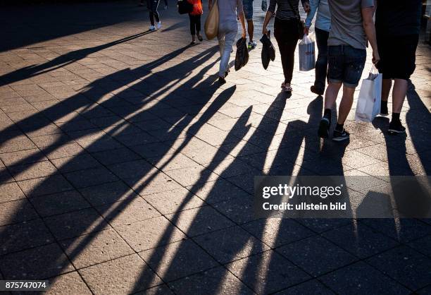 Deutschland Germany Berlin Menschen mit Einkauftüten werfen ihre Schatten auf den Bürgersteig des Kuhdammes.